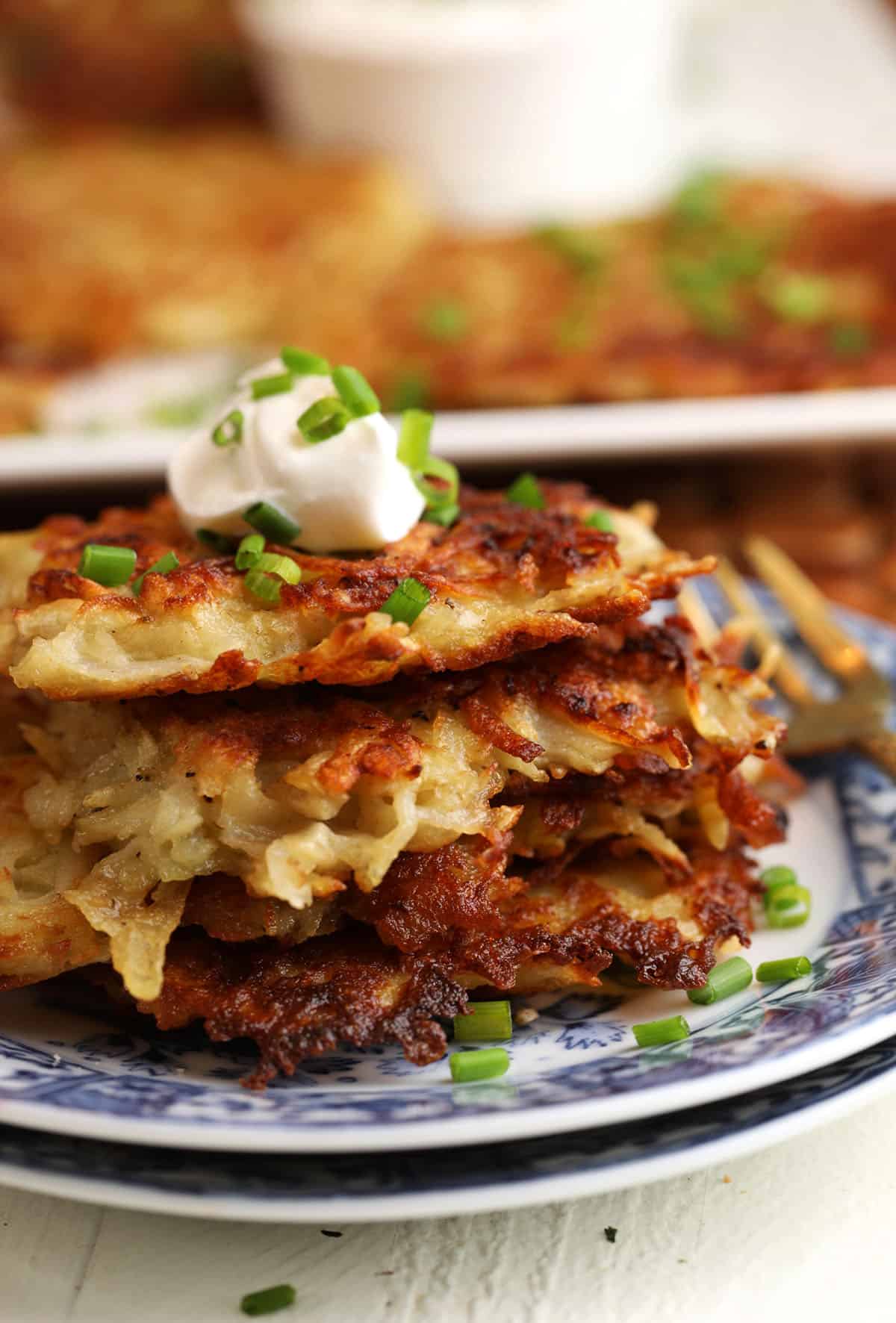 Polish potato pancakes stacked on plate with sour cream on top