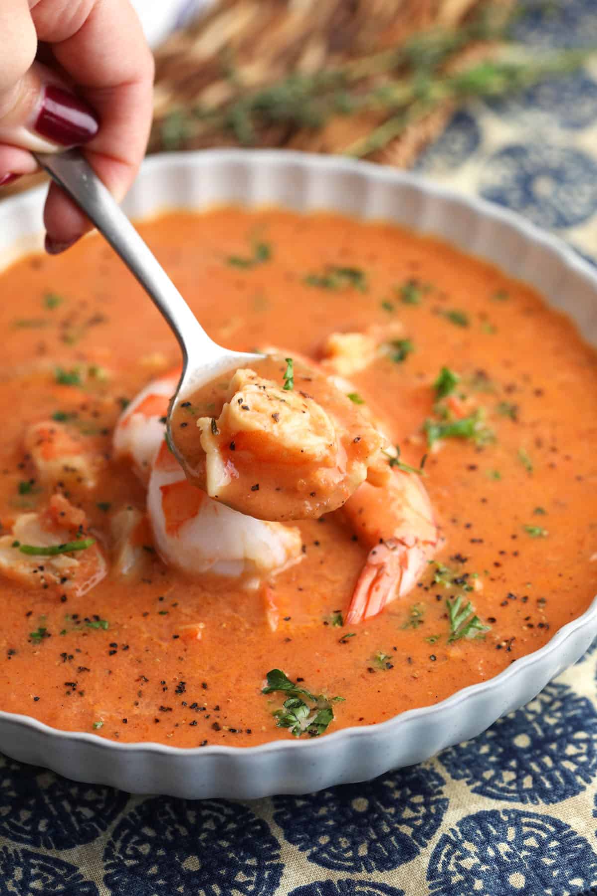 Spoonful of shrimp bisque held over bowl