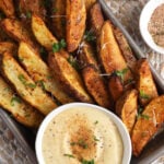 Overhead view of air fryer potato wedges with sauce