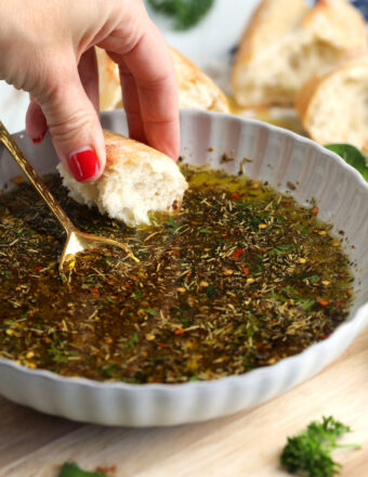 Hand dipping bread into garlic Parmesan oil