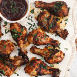 Overhead view of air fryer chicken legs with garlic and Parmesan on platter with sauce