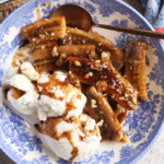 Bananas foster in bowl with scoops of vanilla ice cream and spoon
