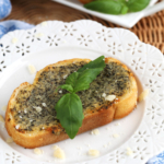 Slice of garlic toast on plate with basil for garnish
