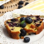 Slice of blueberry lemon pound cake on plate with fresh blueberries