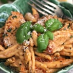 Bowl of marry me chicken pasta with fork and sprig of basil for garnish