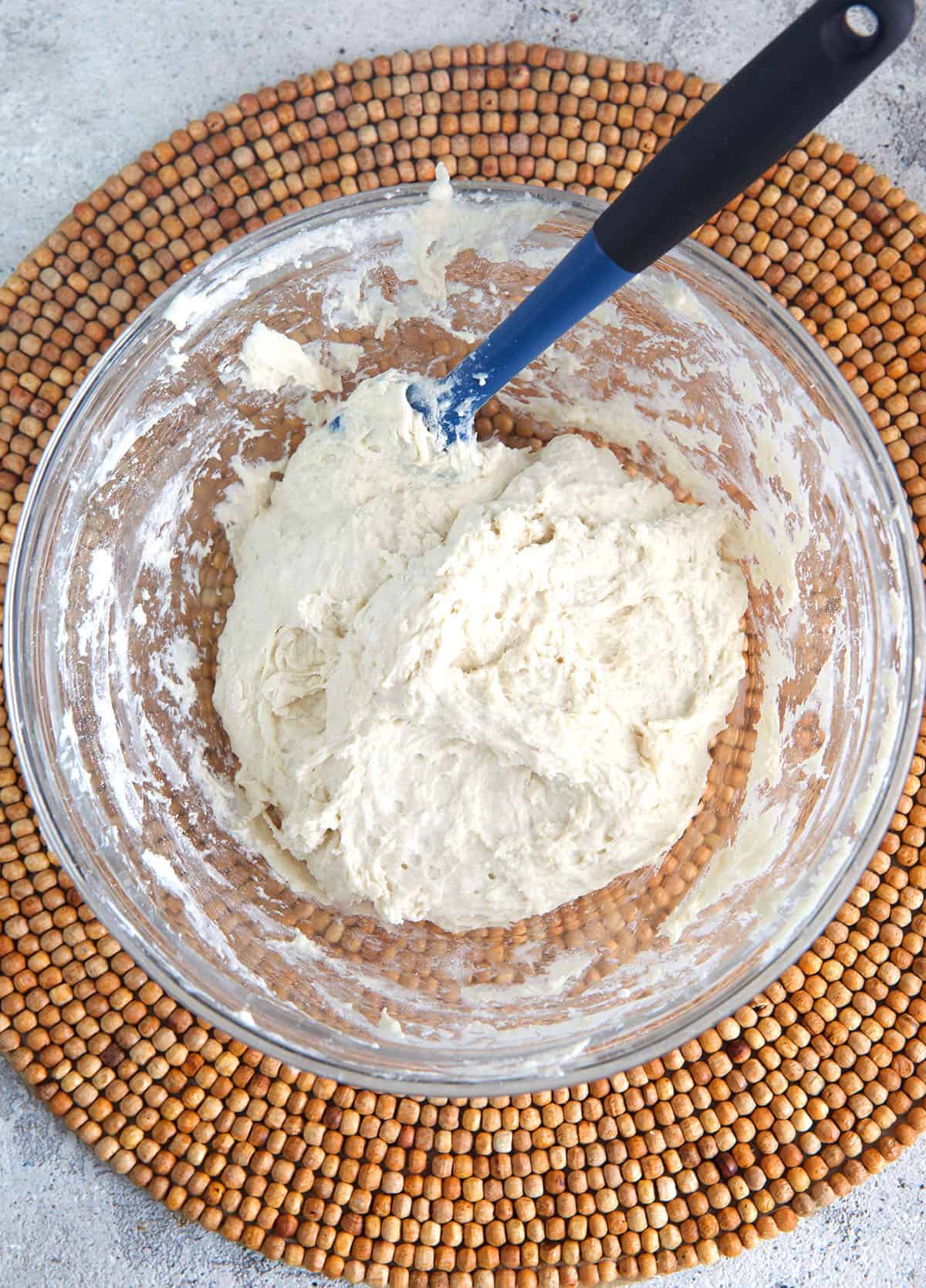 biscuit dough in a mixing bowl with a blue spatula