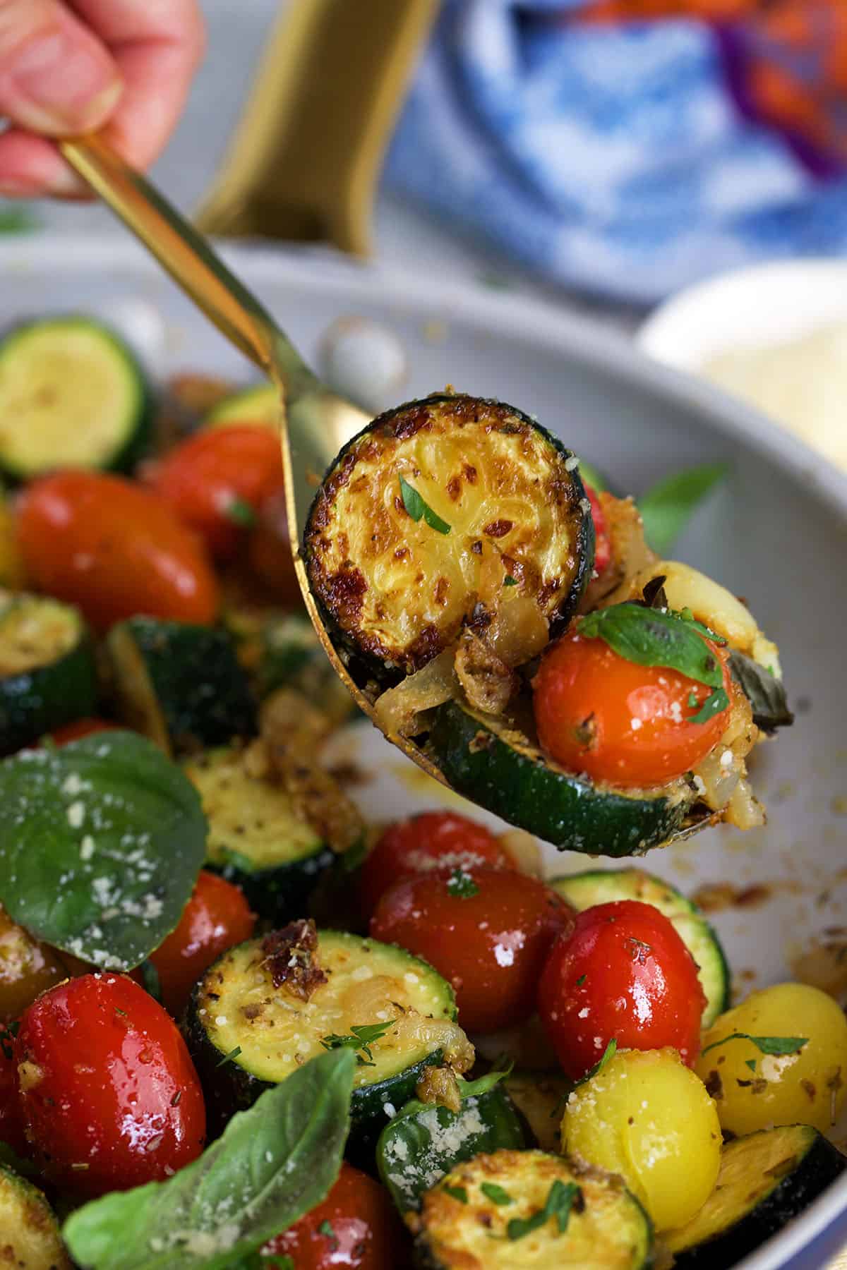 Sautéed zucchini with tomatoes and basil on a gold serving spoon