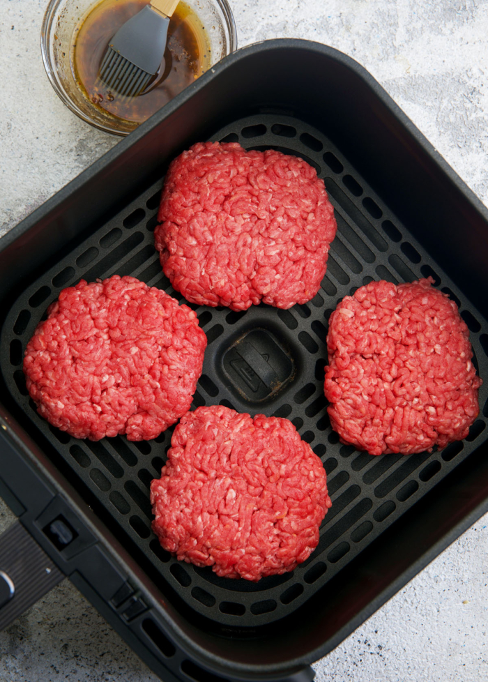 burger patties in a basket of an air fryer