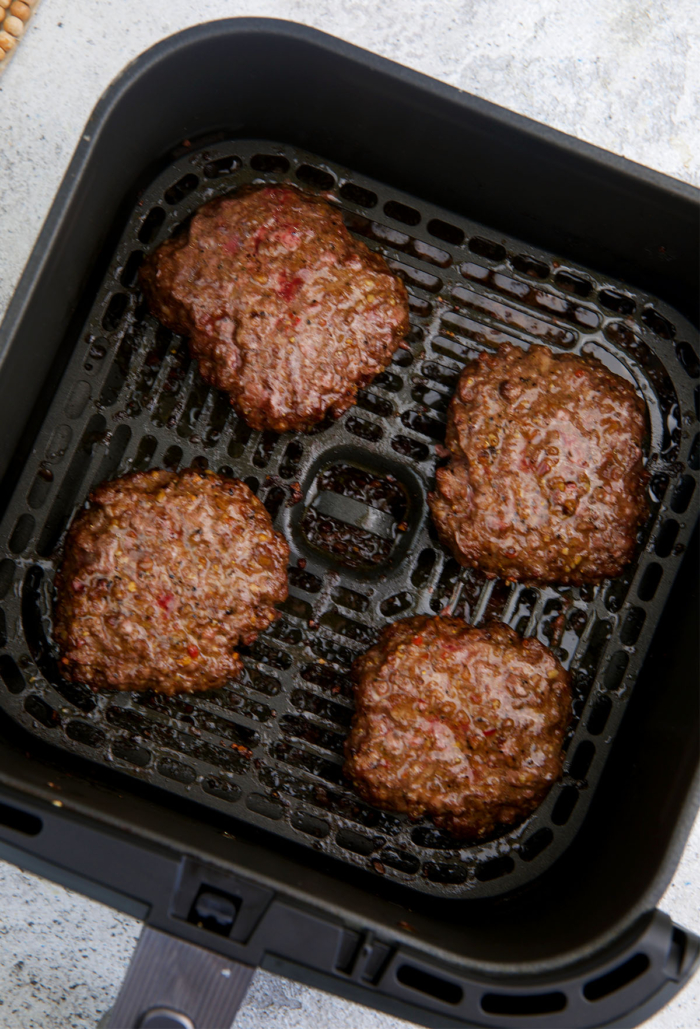 burger patties cooked in an air fryer basket