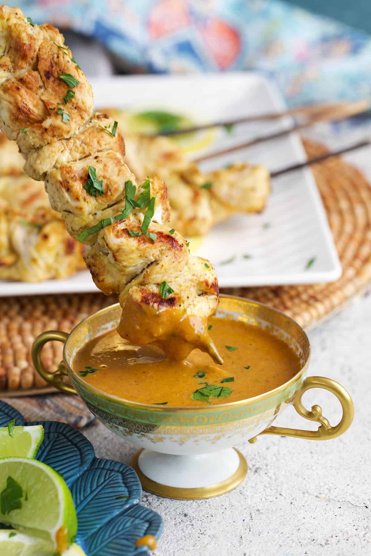Chicken Satay being dipped into a bowl of peanut sauce.