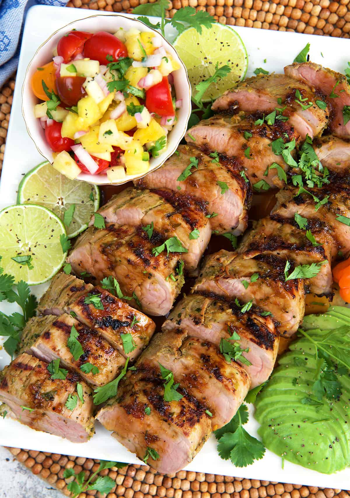 Jamaican jerk Pork sliced on a platter with a bowl of pico de Gallo
