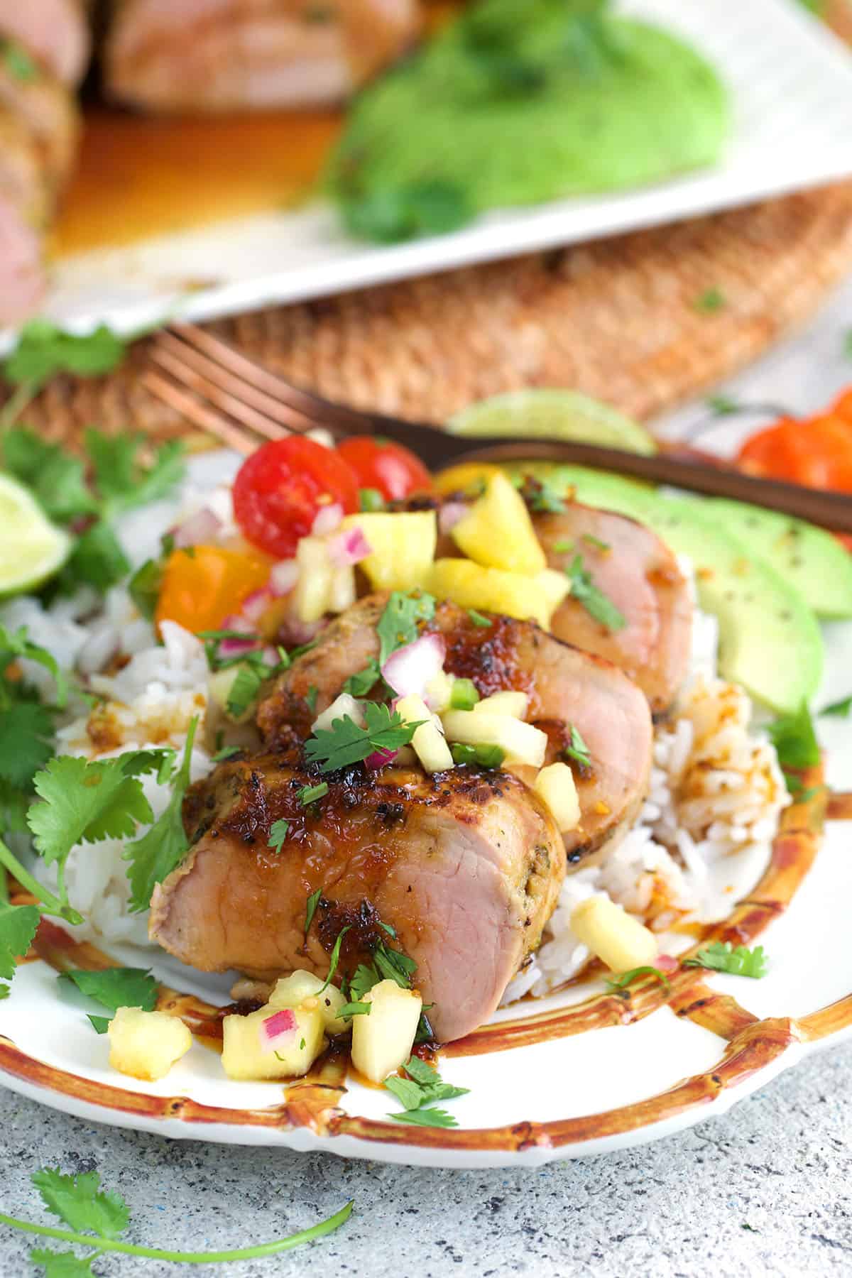 Jerk Pork plated on a bed of rice and topped with pineapple pico de Gallo