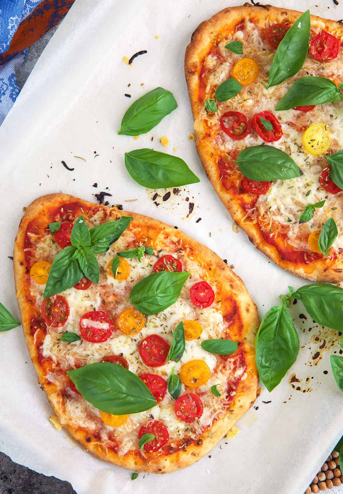 Flatbread pizzas on a baking sheet after being baked in the oven.