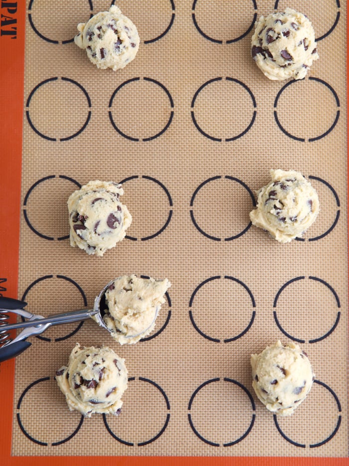 cookie dough on a baking liner with a cookie scoop