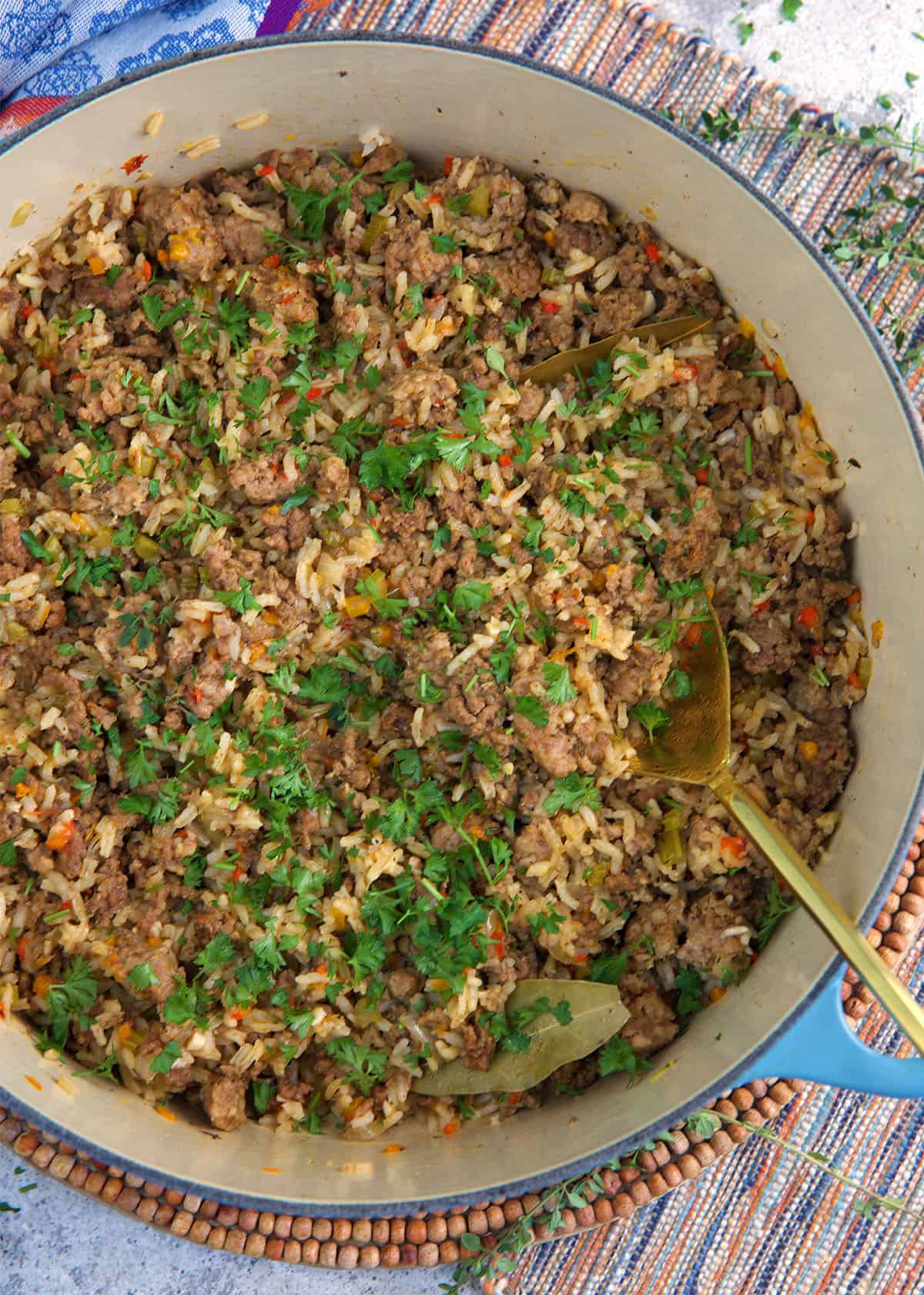 Cajun Dirty Rice in a dutch oven with a gold serving spoon