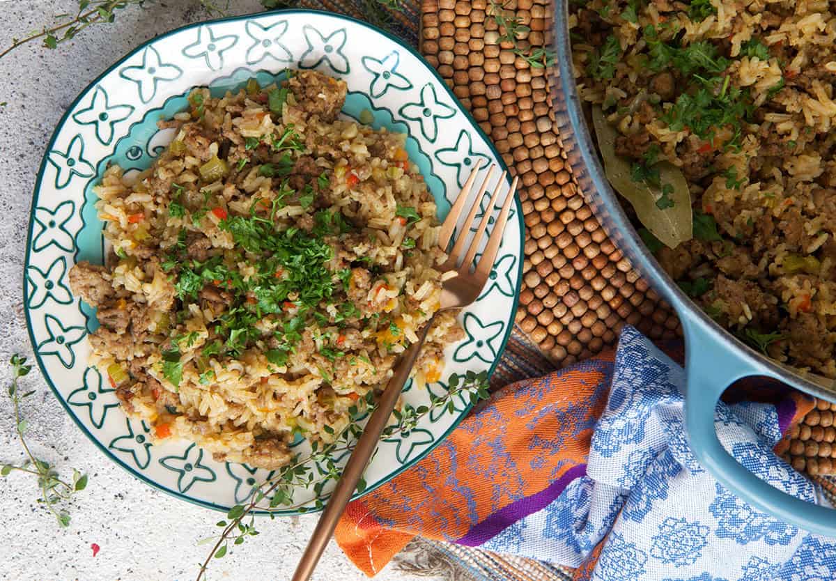 Dirty rice plates on a blue and white plate with a copper fork.