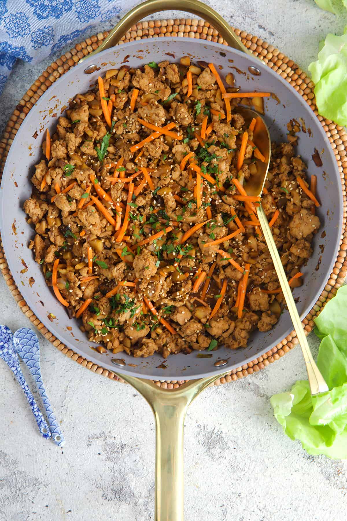 Filling for chicken lettuce wraps in a skillet with a wooden spoon