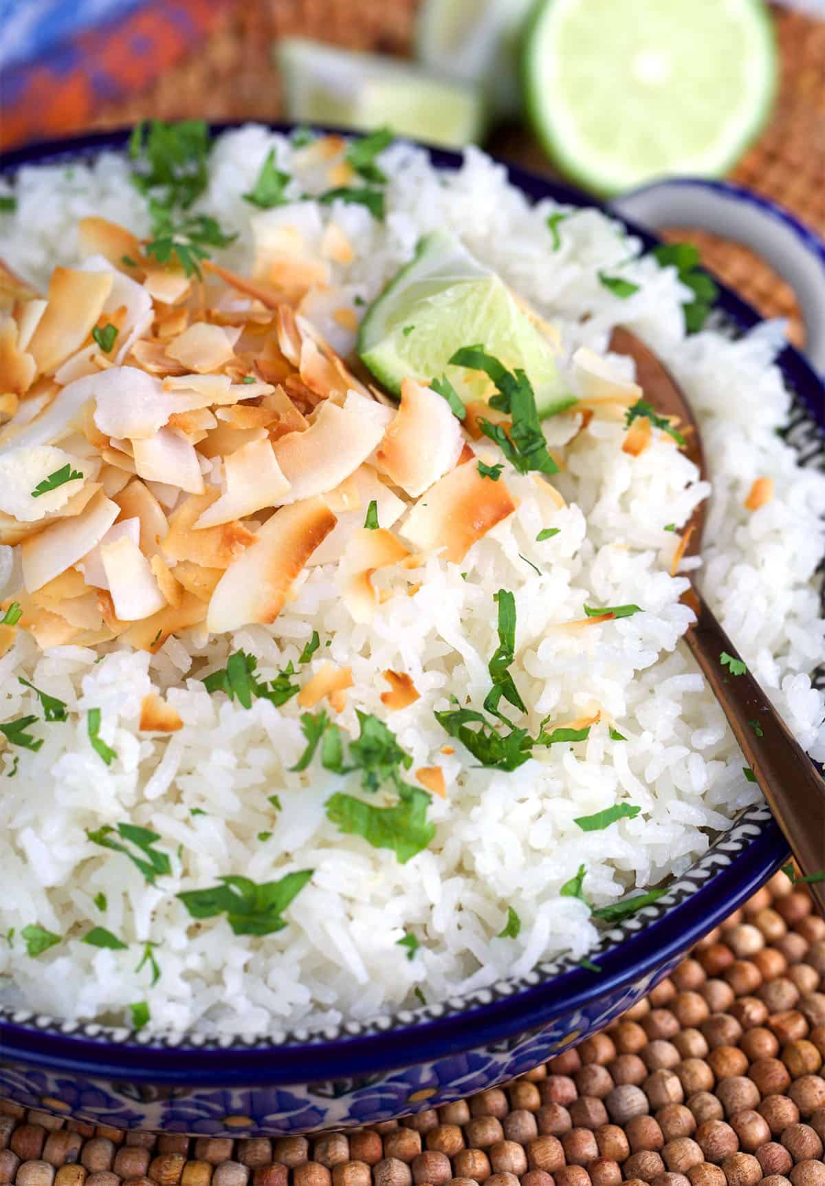 coconut rice topped with coconut flakes with a lime half in the background.