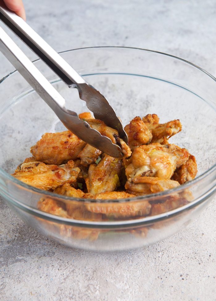 Lemon Pepper Wings being tossed in a bowl