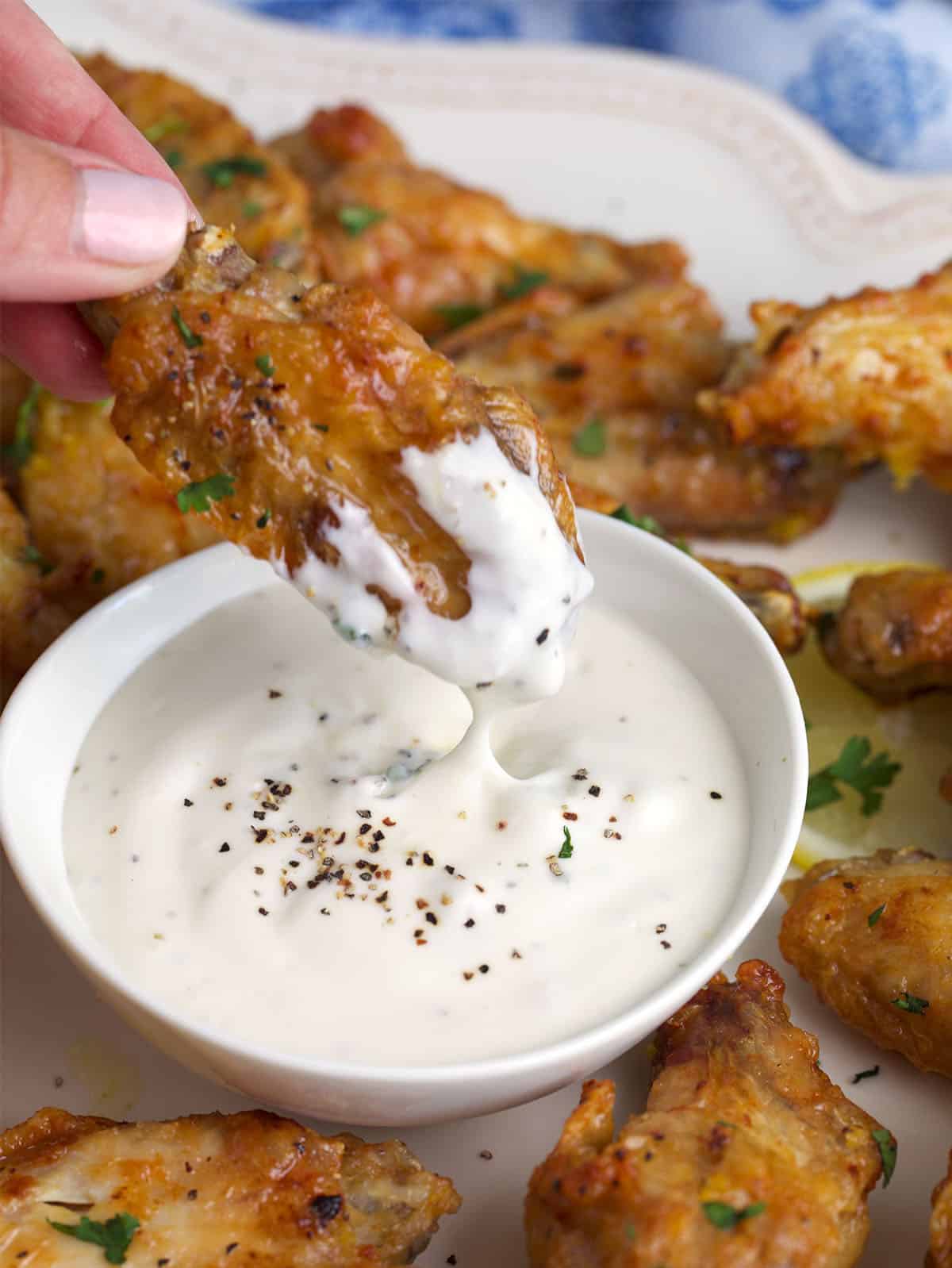 Lemon Pepper Chicken Wings being dipped into sauce.