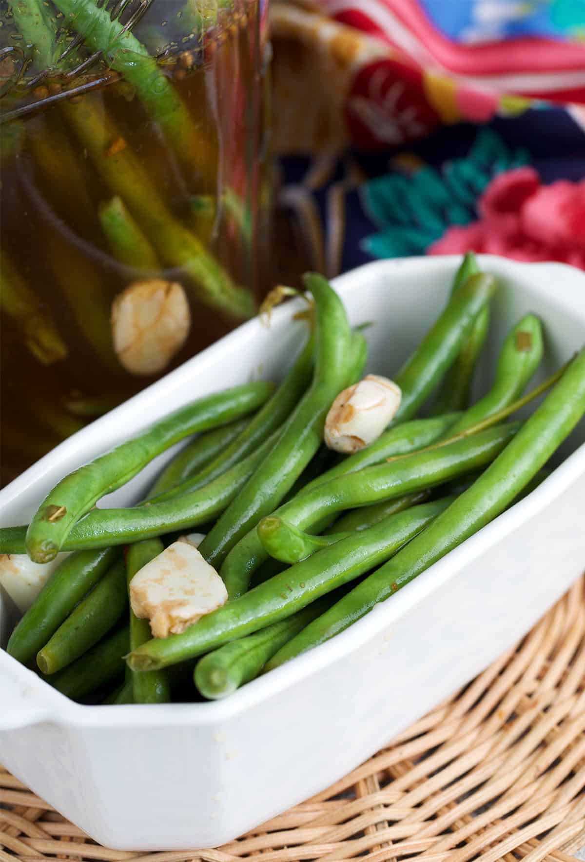 pickled green beans in a white serving dish with pickled garlic cloves.