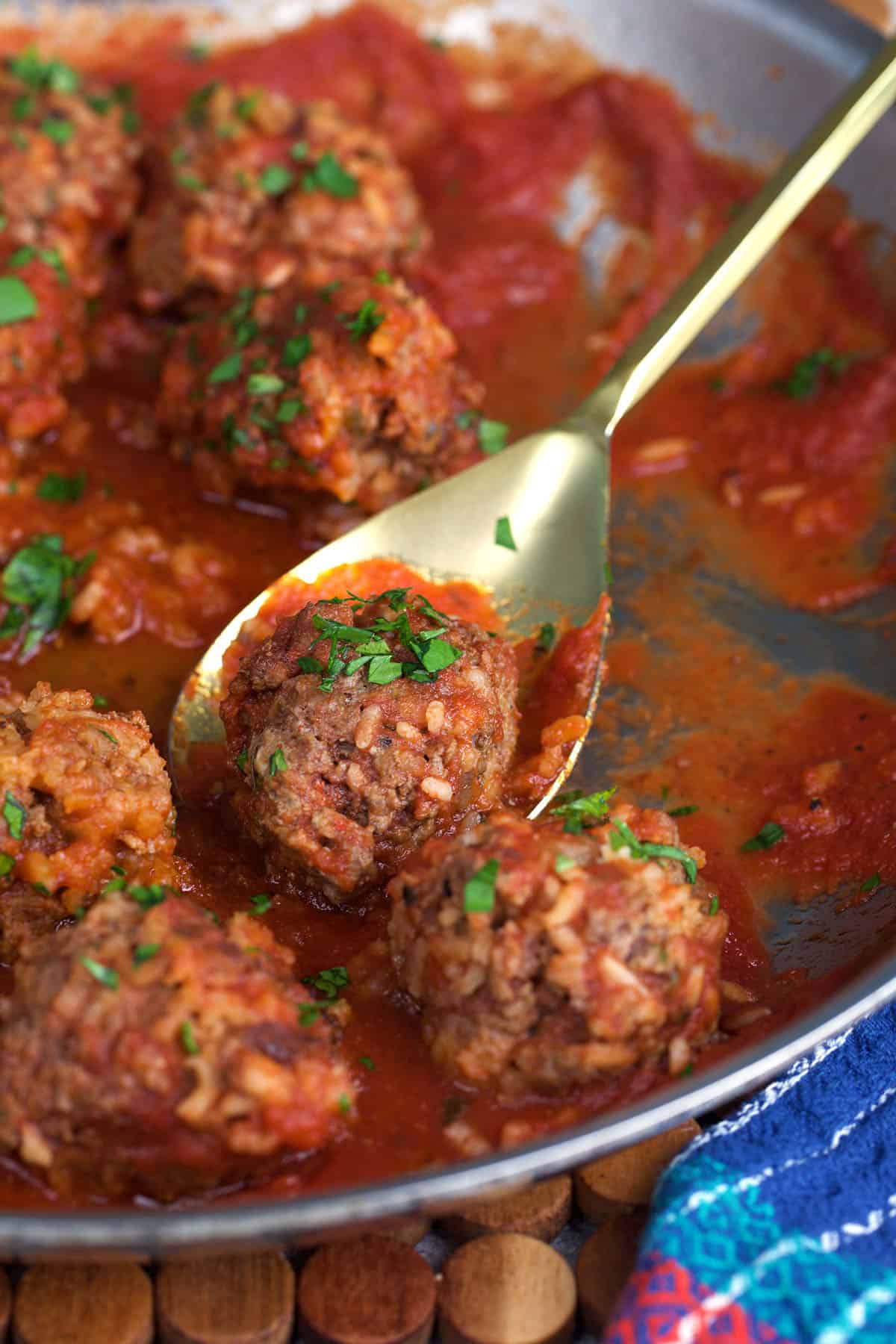 Porcupine Meatballs in a skillet with one on a spoon