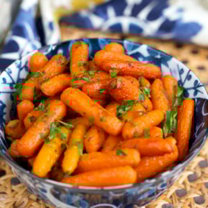 Roasted Baby Carrots in a blue and white bowl with parsley on top.