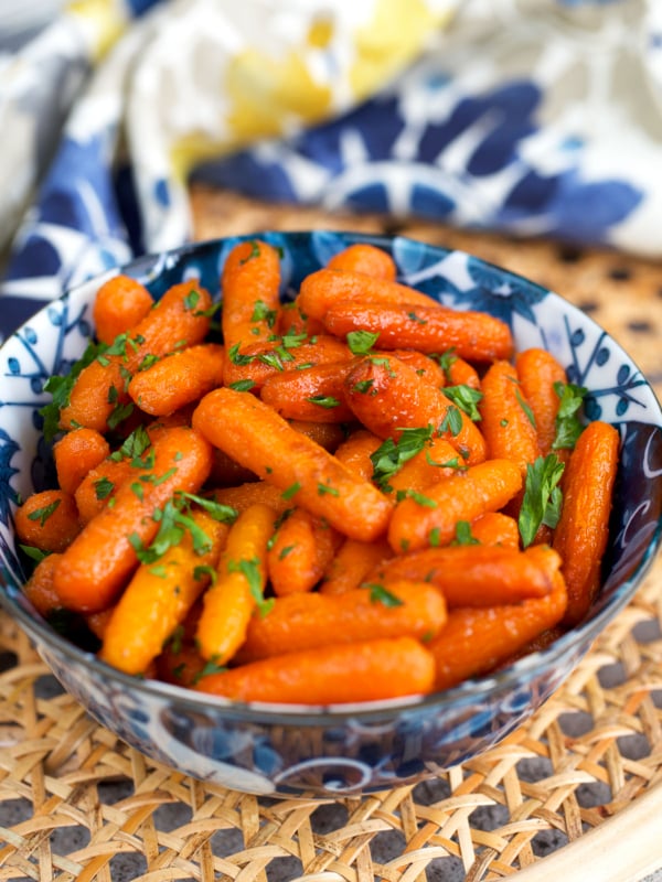 Roasted Baby Carrots in a blue and white bowl with parsley on top.