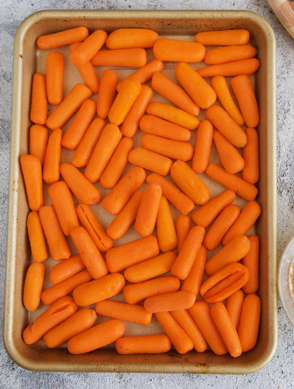 raw baby carrots on a baking sheet ready to be roasted 