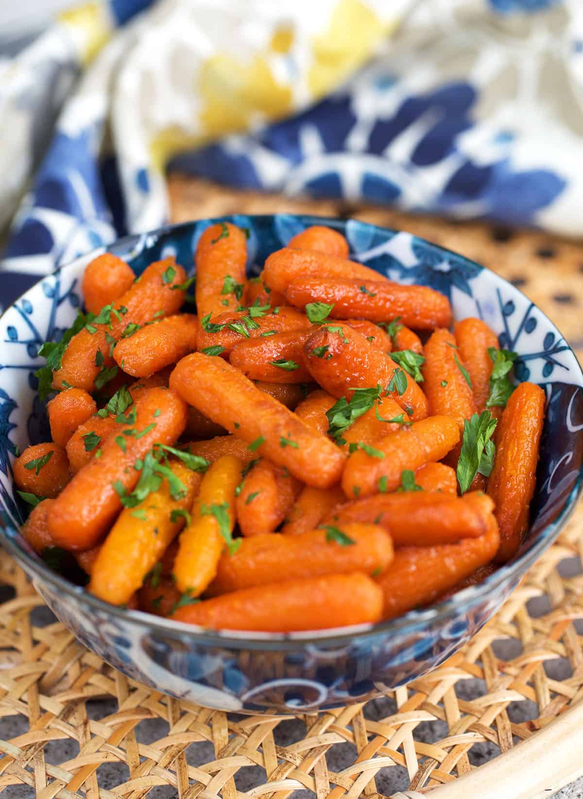 Roasted Baby Carrots in a blue and white bowl with parsley on top.