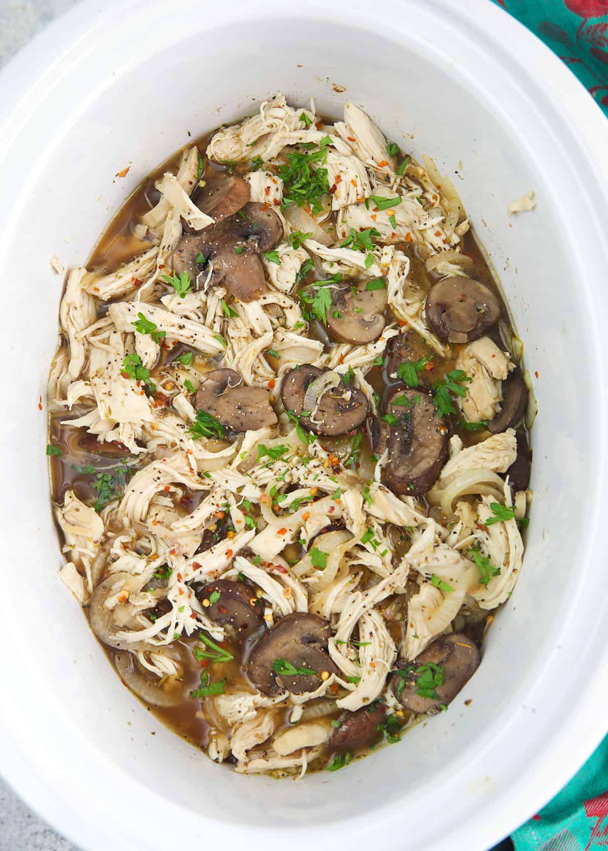 shredded chicken breast in onions and broth ready to be served on long rolls