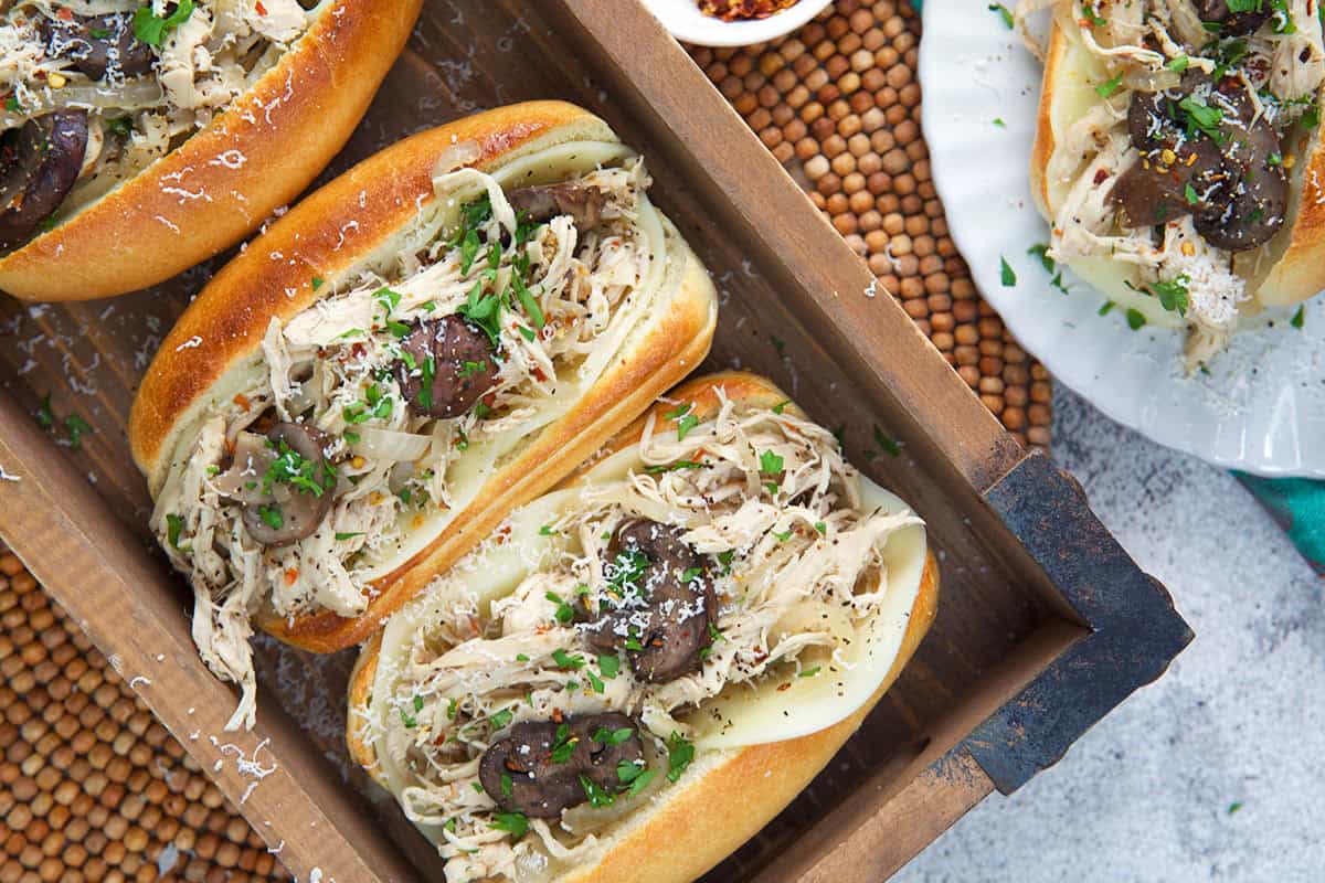 Three chicken cheesesteaks in a wood box.