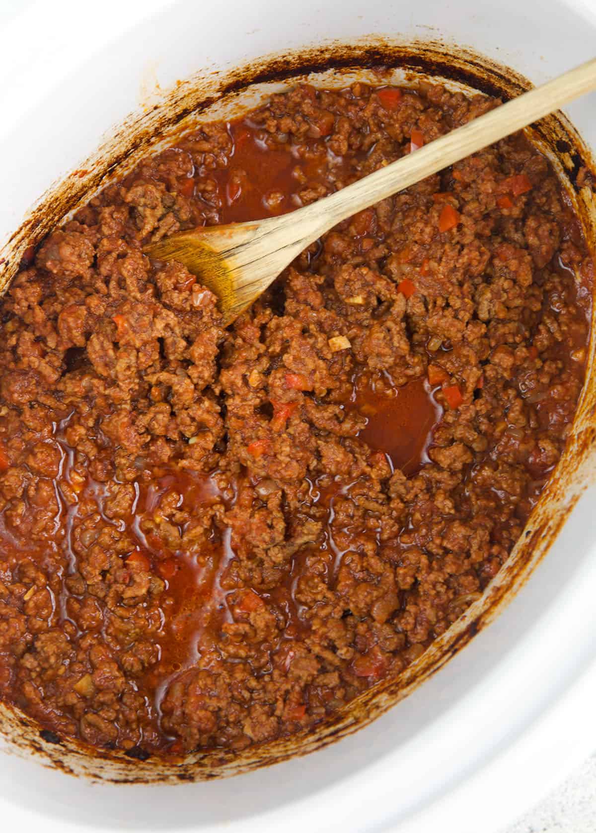slow cooker sloppy Joe in a crock pot with a wooden spoon.
