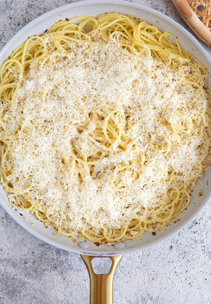 process of pasta with olive oil and garlic being cooked with cheese sprinkled on top