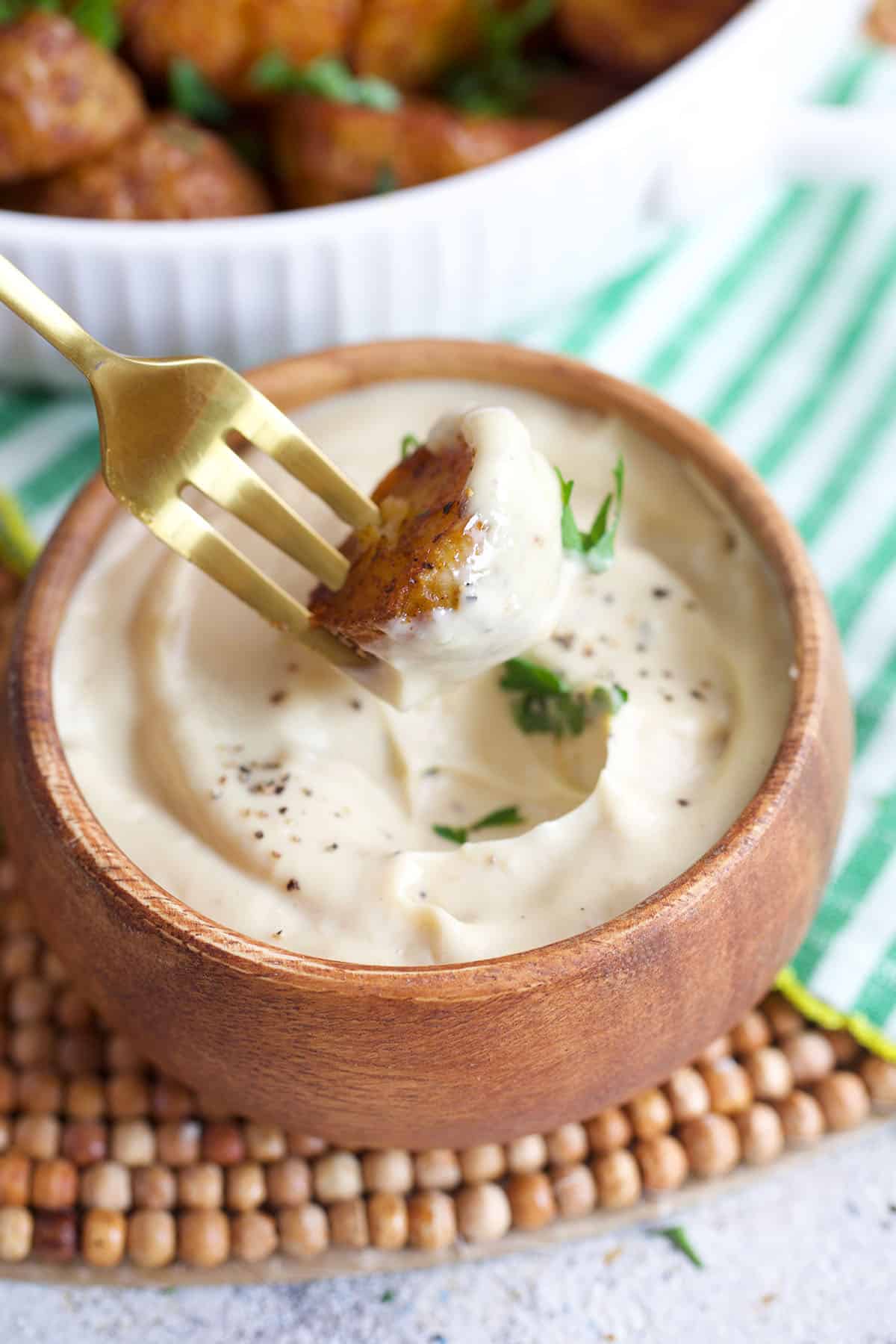 Air Fryer Roasted potato on a fork being dipped into a bowl of aioli
