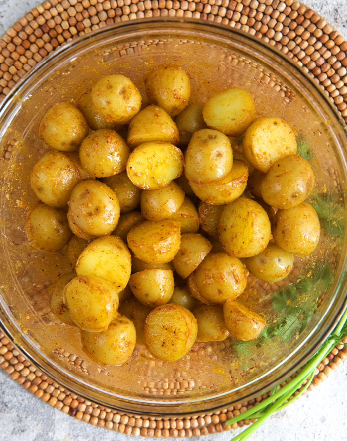 baby potatoes in a mixing bowl being tossed with cornstarch spice blend
