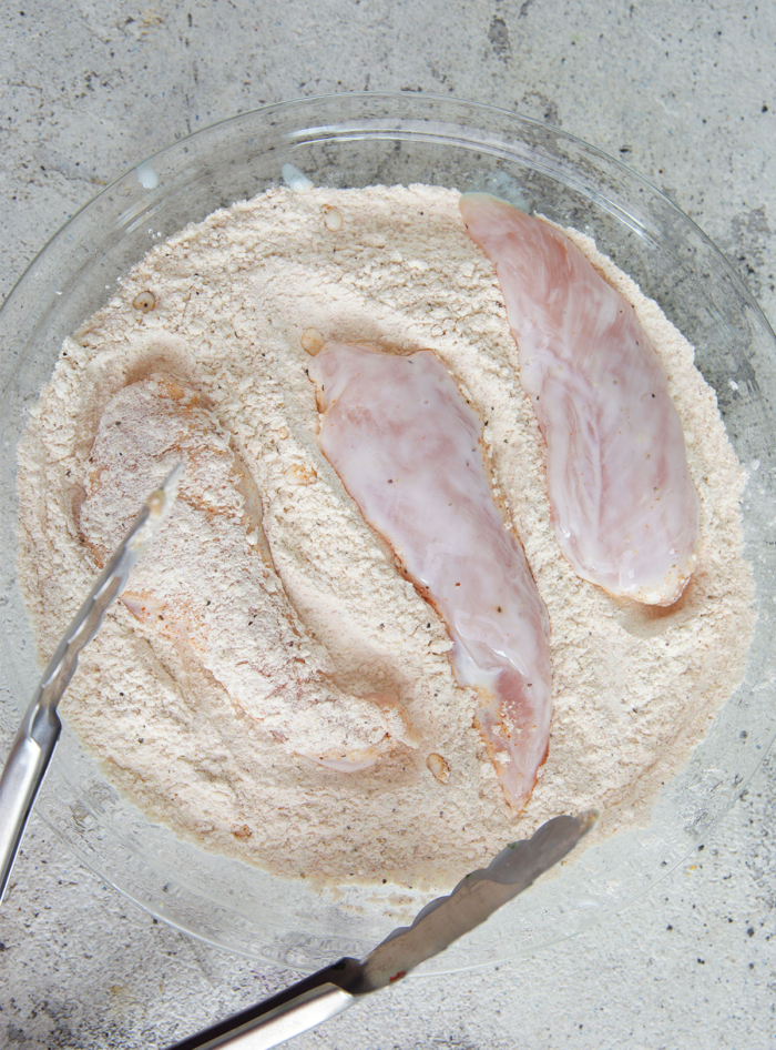 chicken tenders being dreaded in flour mixture