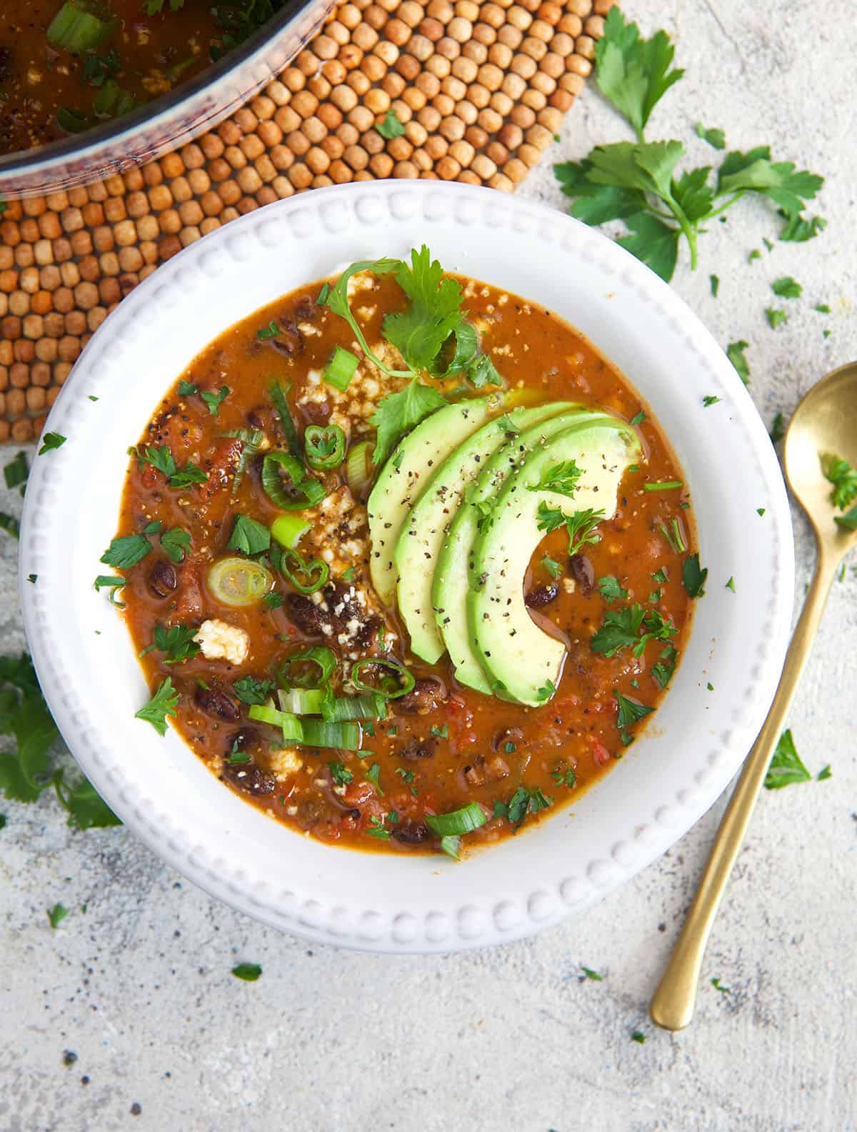 Black Bean Soup in a white bowl with avocado on top