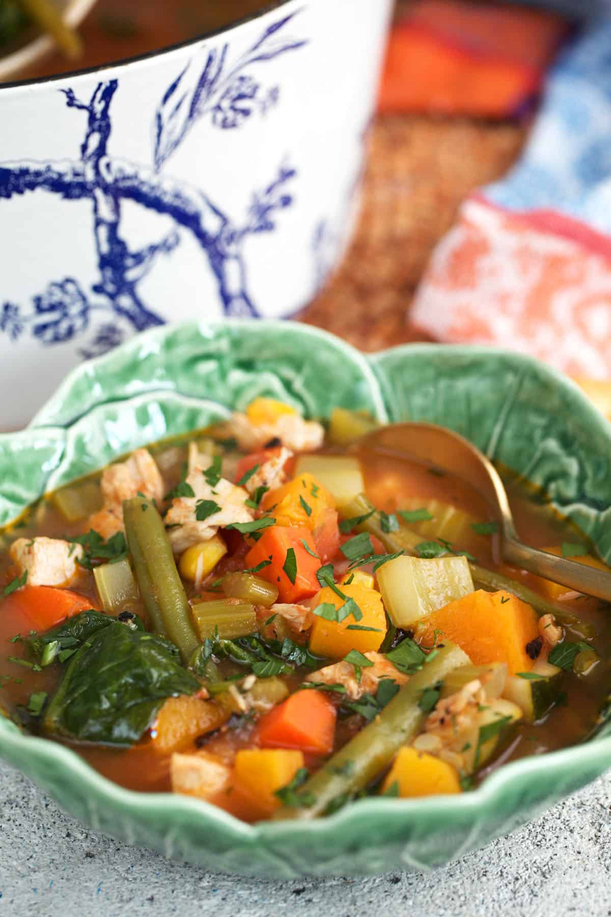 best chicken vegetable soup recipe ever in a cabbage bowl with a dutch oven behind it.