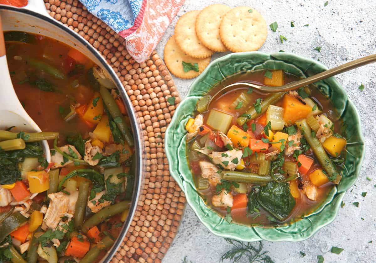 chicken soup with vegetables in a cabbage bowl with a dutch oven for serving.