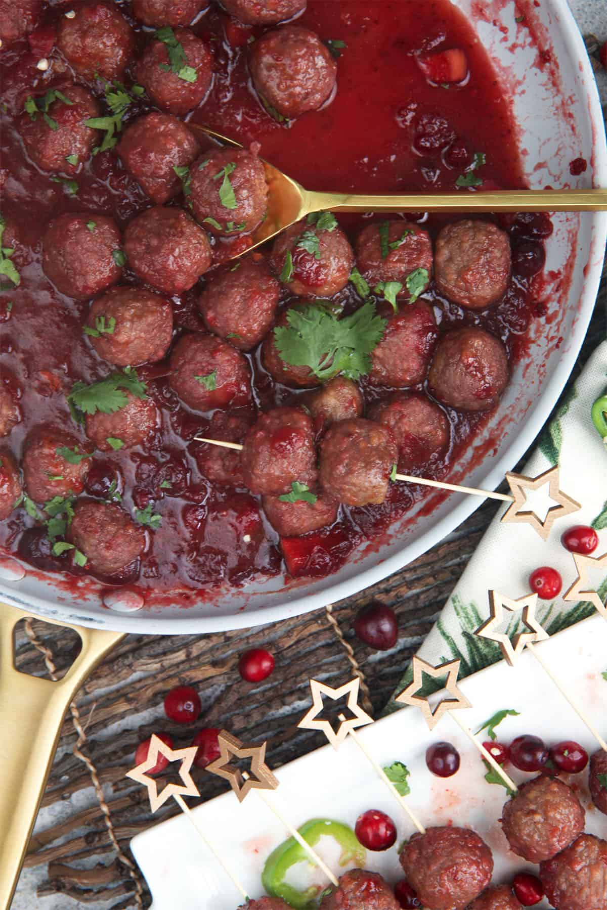 cranberry jalapeno meatballs in a skillet with a serving spoon