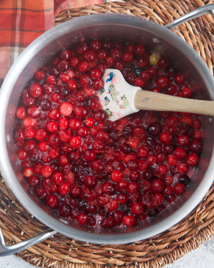 cranberries being cooked in a saucepan for cranberry sauce.