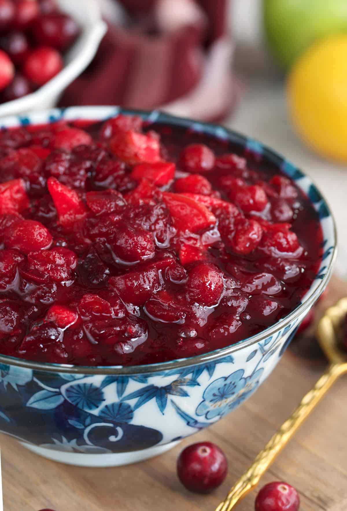Homemade cranberry sauce in a blue and white bowl with a gold spoon.