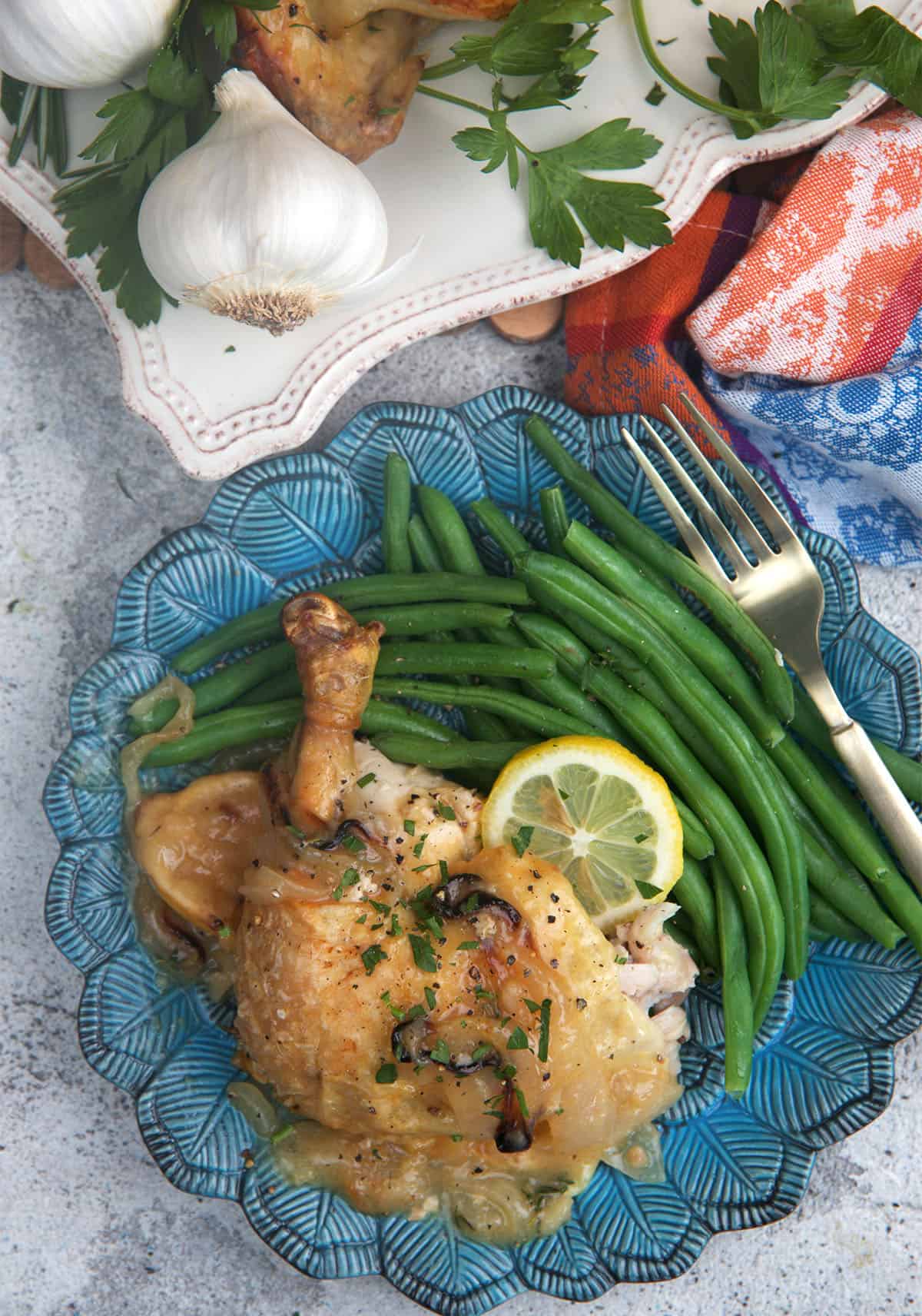 Roast chicken leg on a plate with green beans.