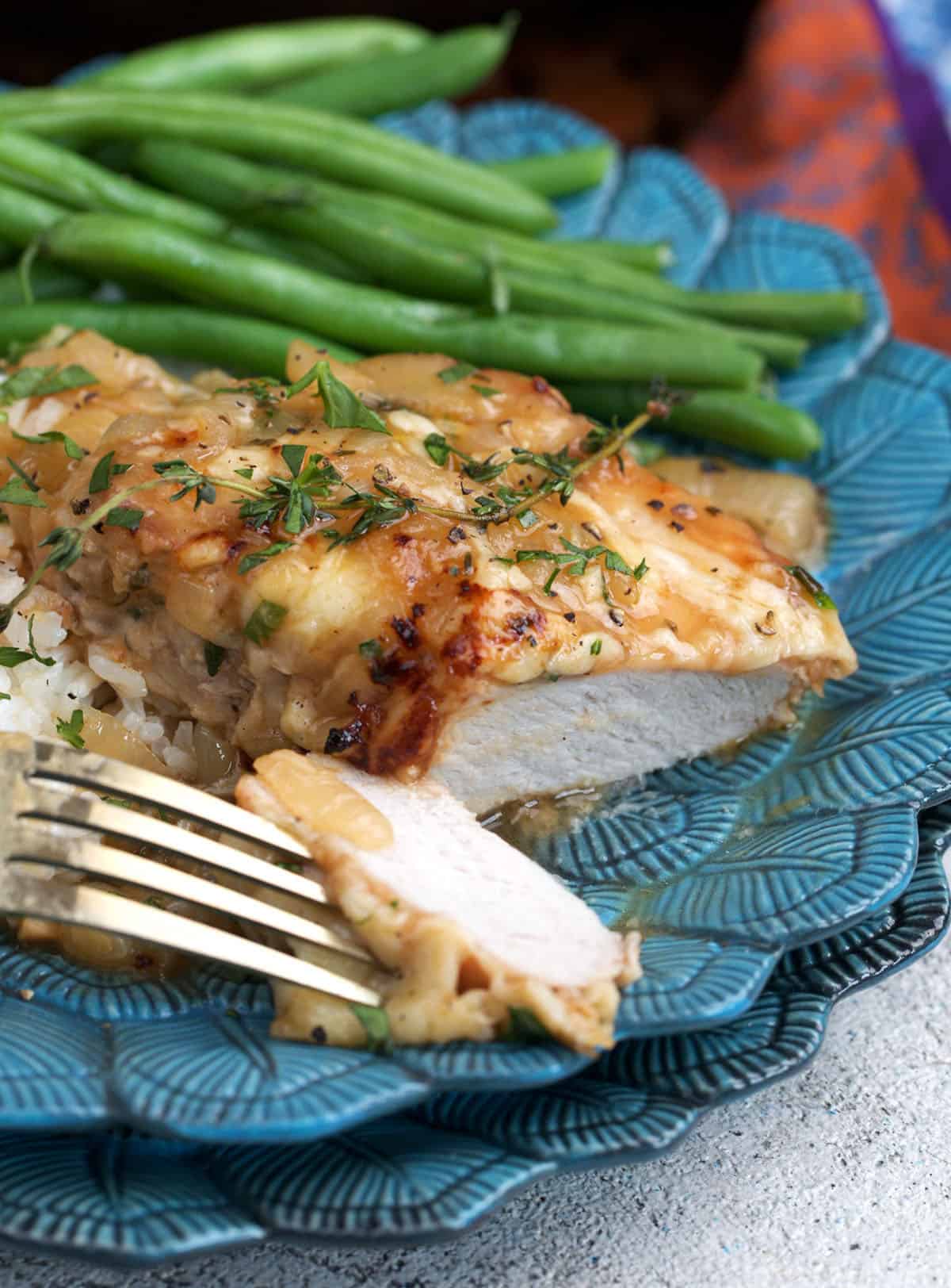 French onion pork chop with a bite on a fork.