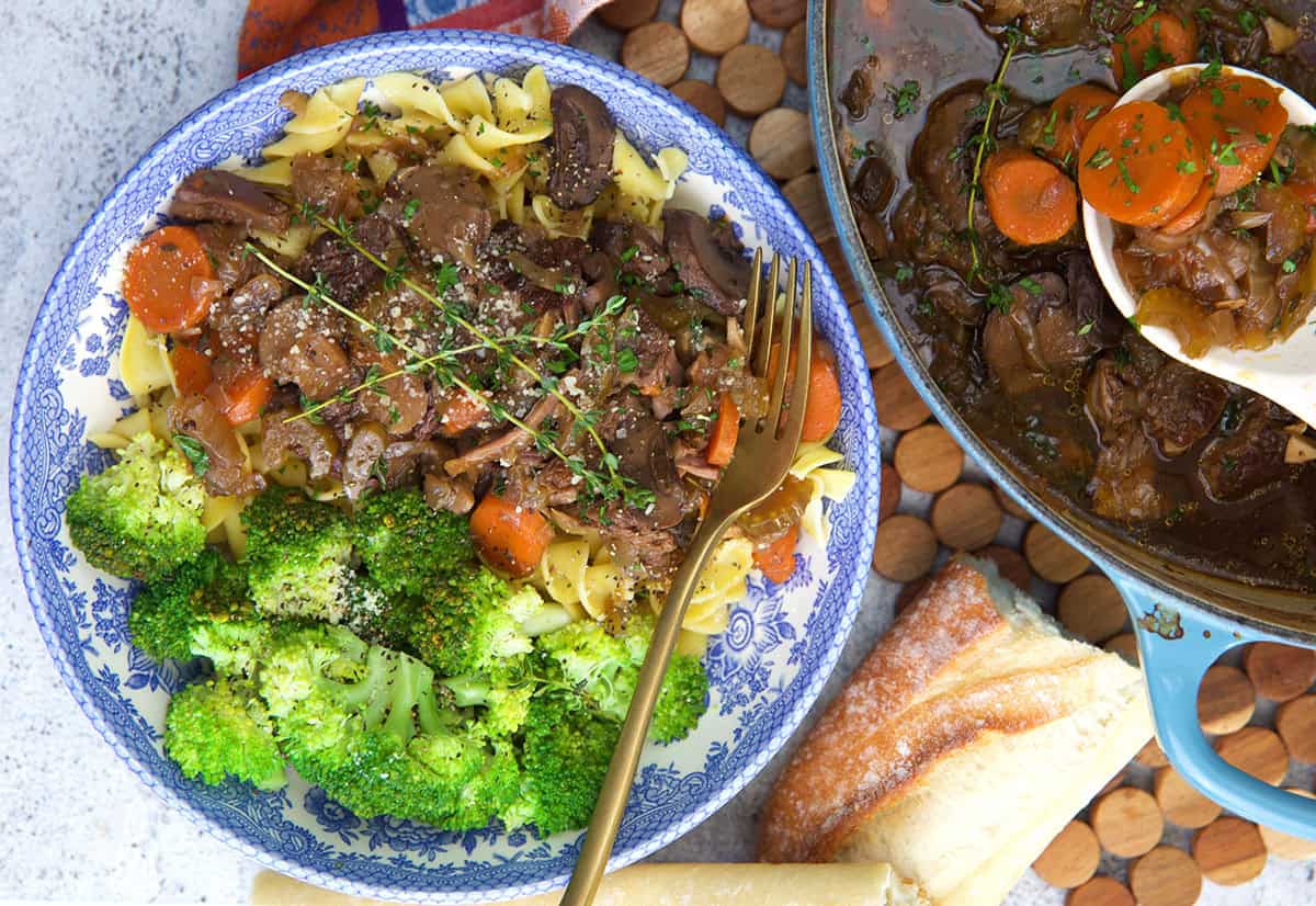 French Onion Pot Roast recipe in a bowl with broccoli next to the pot with a serving spoon