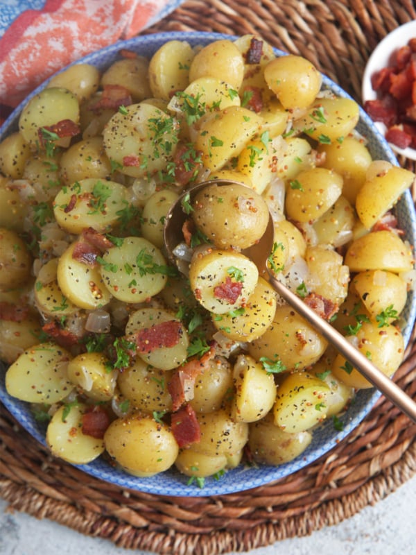 Hot German Potato Salad in a serving bowl with a copper spoon