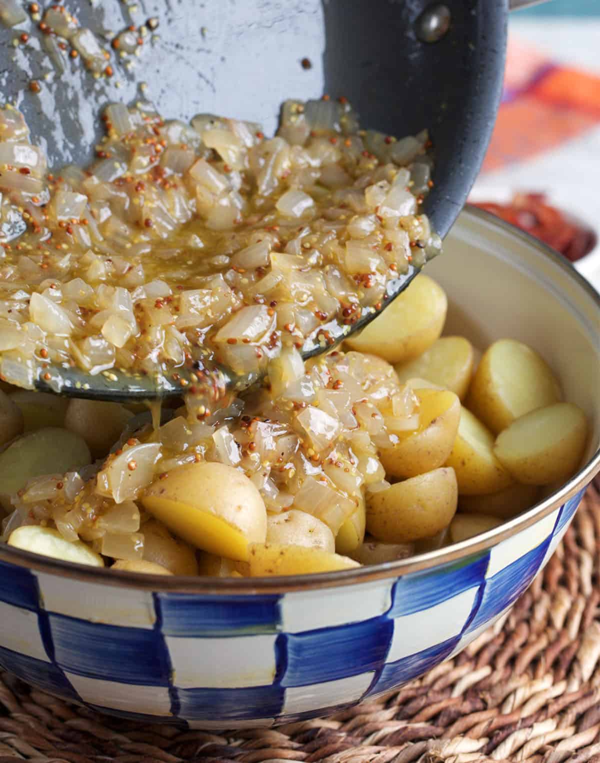 bacon dressing being poured over potatoes for German potato salad