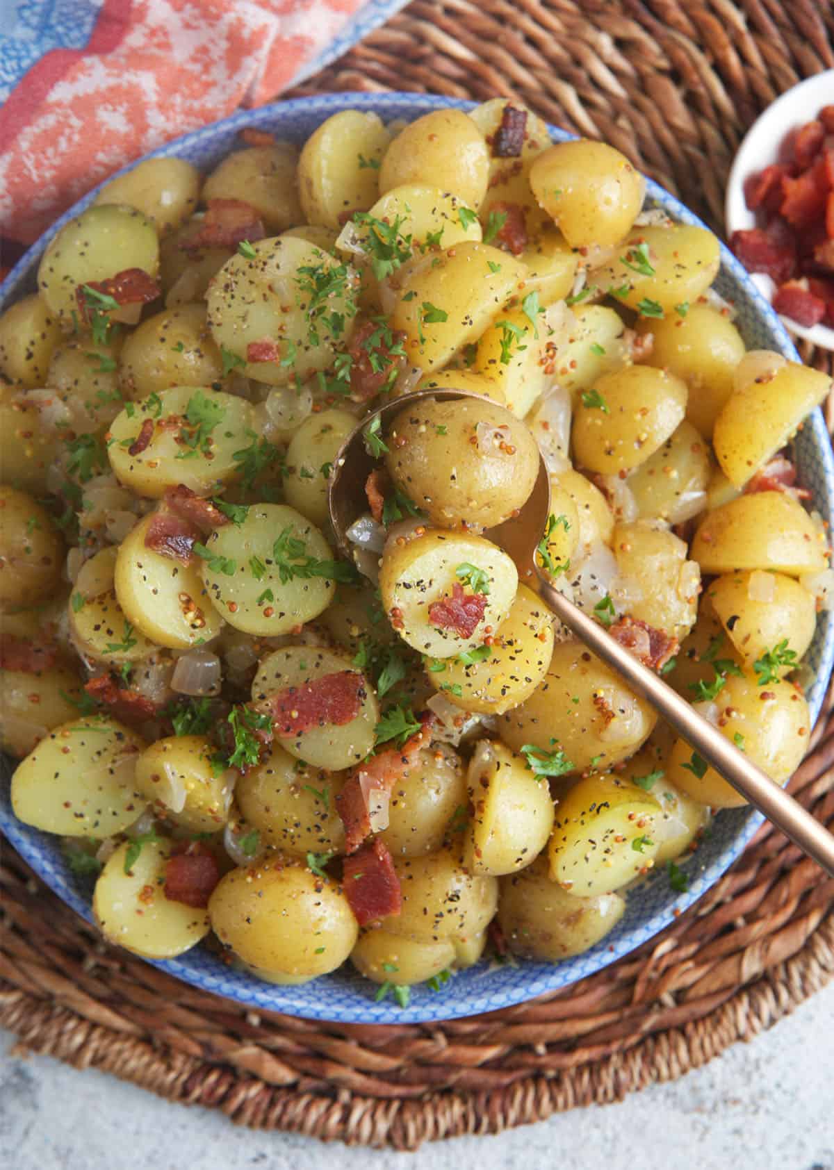 Hot German Potato Salad in a serving bowl with a copper spoon