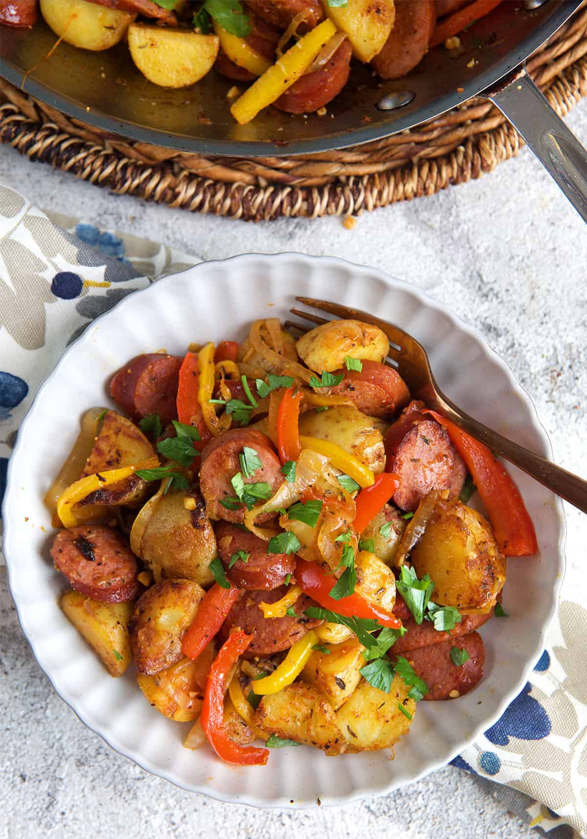 a serving of kielbasa and potatoes in a white plate.